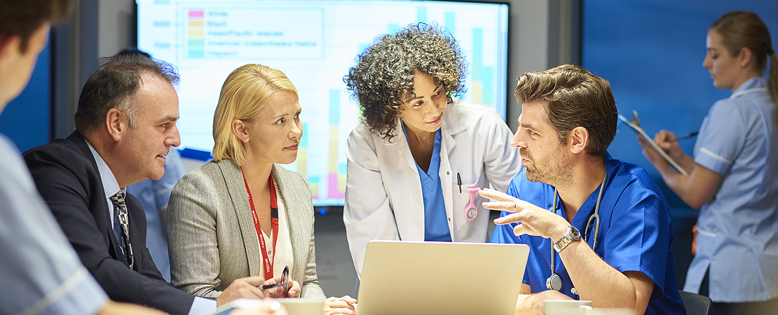 Group of healthcare colleagues sitting around a computer